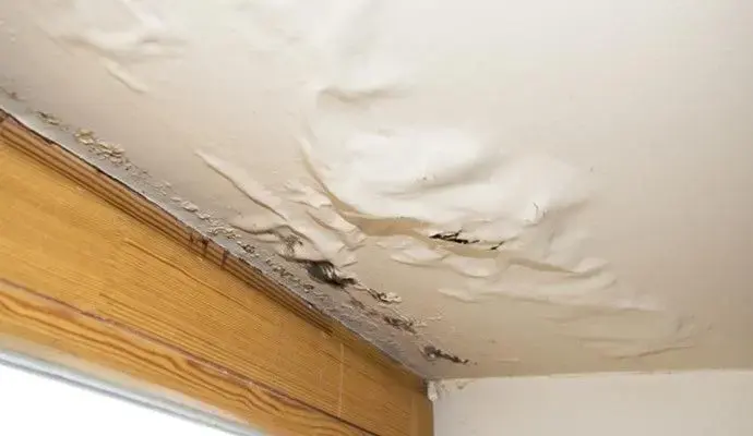 Ceiling paint bubbling from water above a window frame