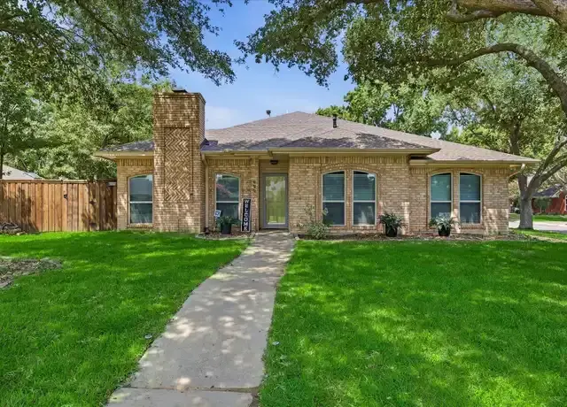Brick single-story home with a front walk and shade trees in a Flower Mound neighborhood